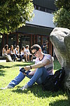 Ein Student liest ein Buch auf der Wiese vor dem Naturwissenschaftlichen Zentrum.
