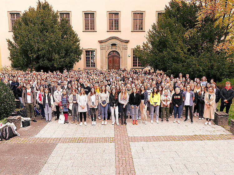 Das Bild zeigt ein rießiges Gruppenbild mit den vielen neuen Studierenden der PH Weingarten. Das Foto wurde aus der Vogelperspektive aufgenommen und zeigt den Innenhof der PH Weingarten in dem sich viele Studierende versammelt haben.