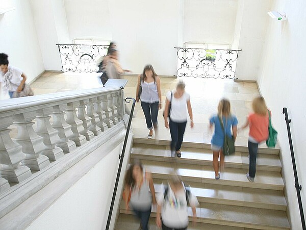 Menschen gehen im barocken Treppenhaus